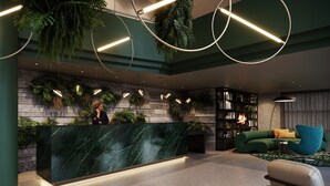 Un área de recepción moderna con mostrador de mármol, paredes verdes y plantas colgantes.