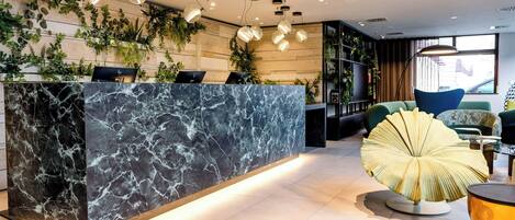 A reception area with a marble counter, pendant lighting, and indoor plants.
