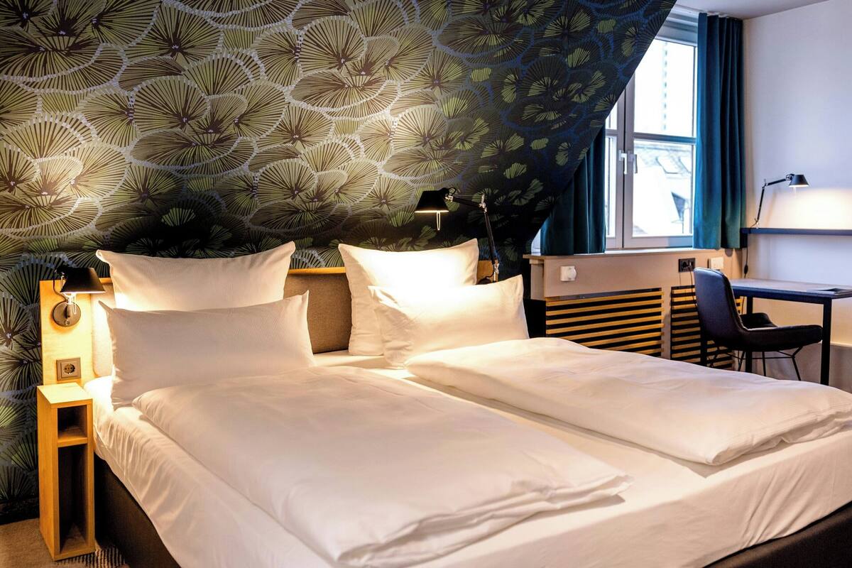 A hotel room with a bed, a desk, and a chair.
