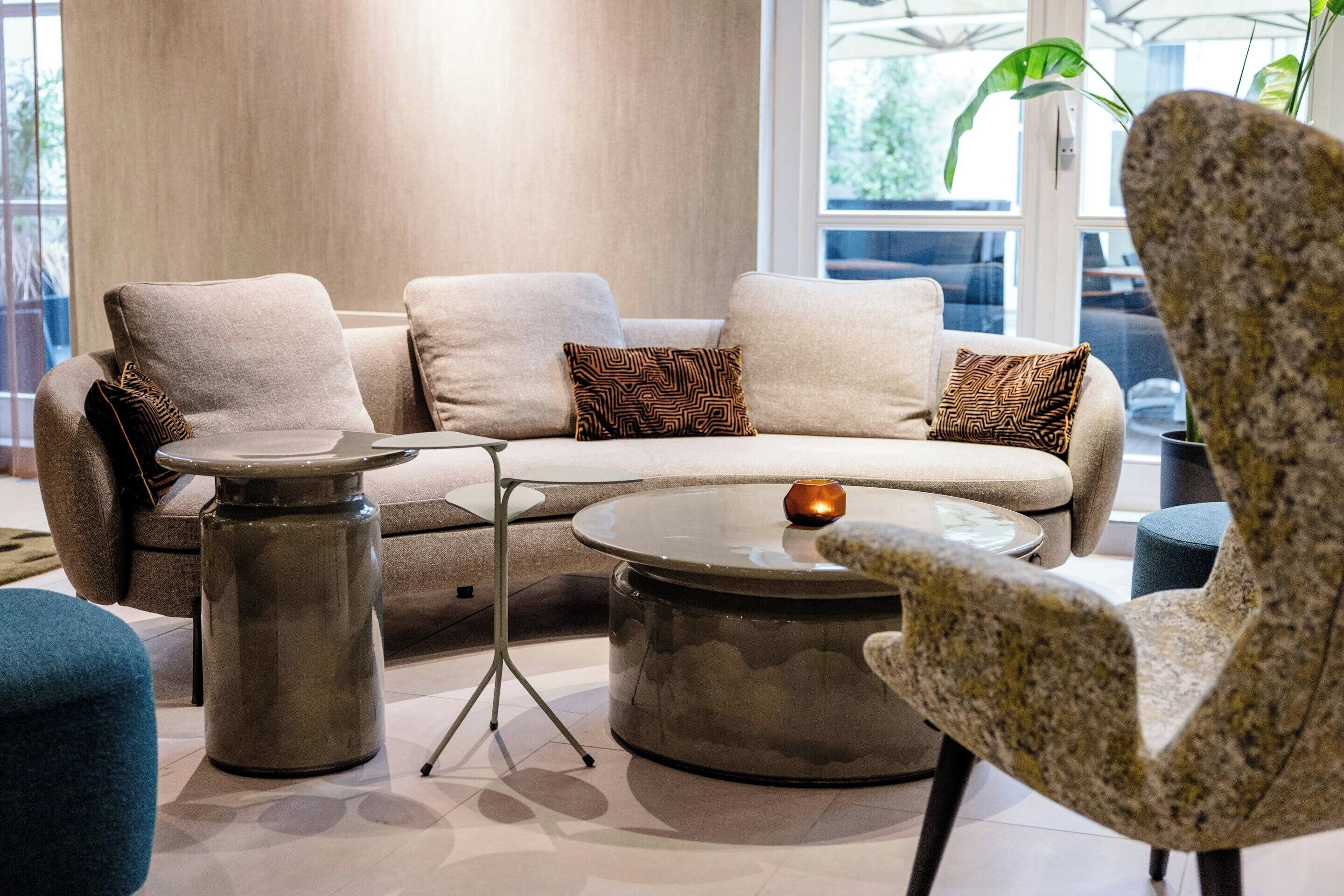 A modern living room with a sectional sofa, two side tables, and a patterned armchair.