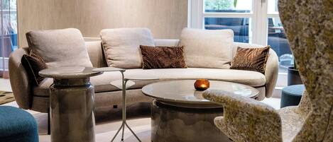 A modern living room with a sectional sofa, two side tables, and a patterned armchair.