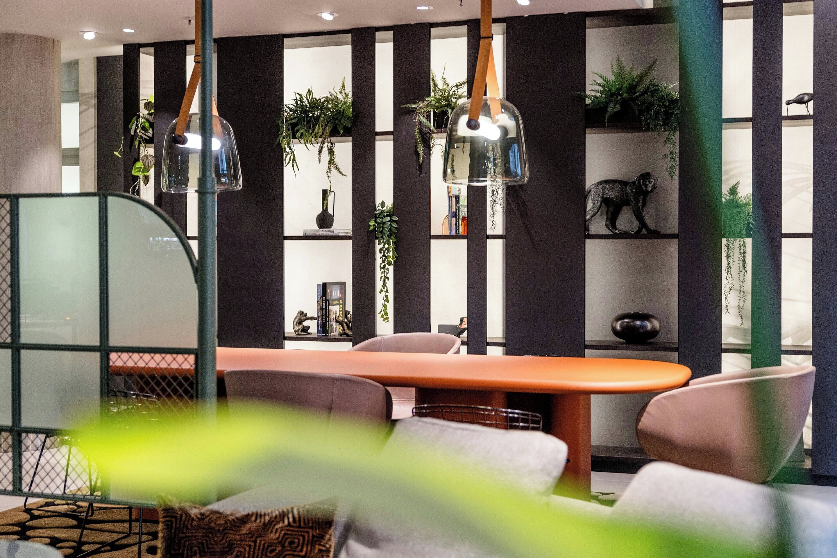 A modern interior with a round table, chairs, and a bookshelf with plants.