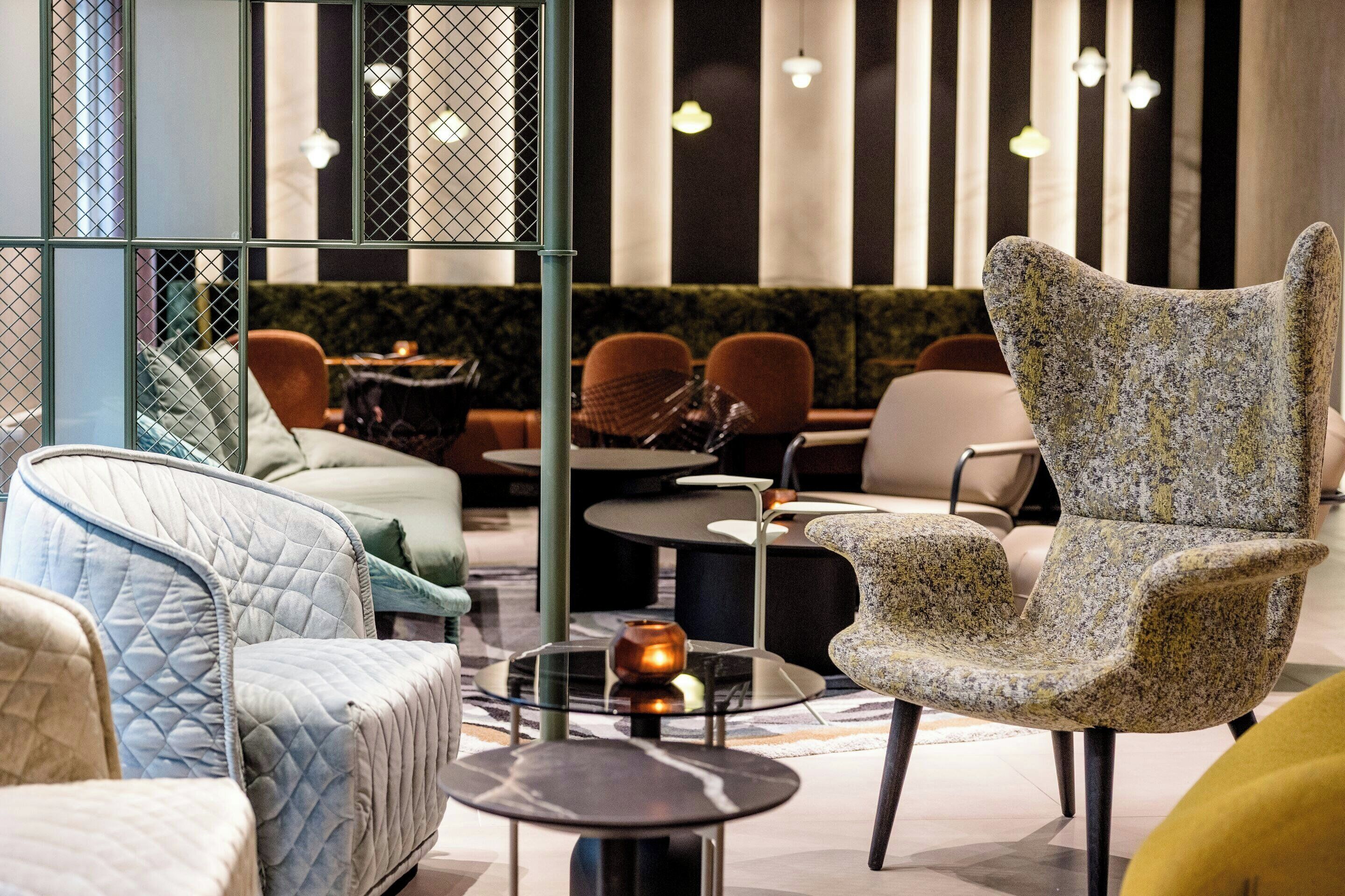 A modern lounge area with seating arrangements, including a patterned armchair and a quilted sofa.