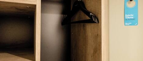 A wooden closet with a metal rod and black hangers.