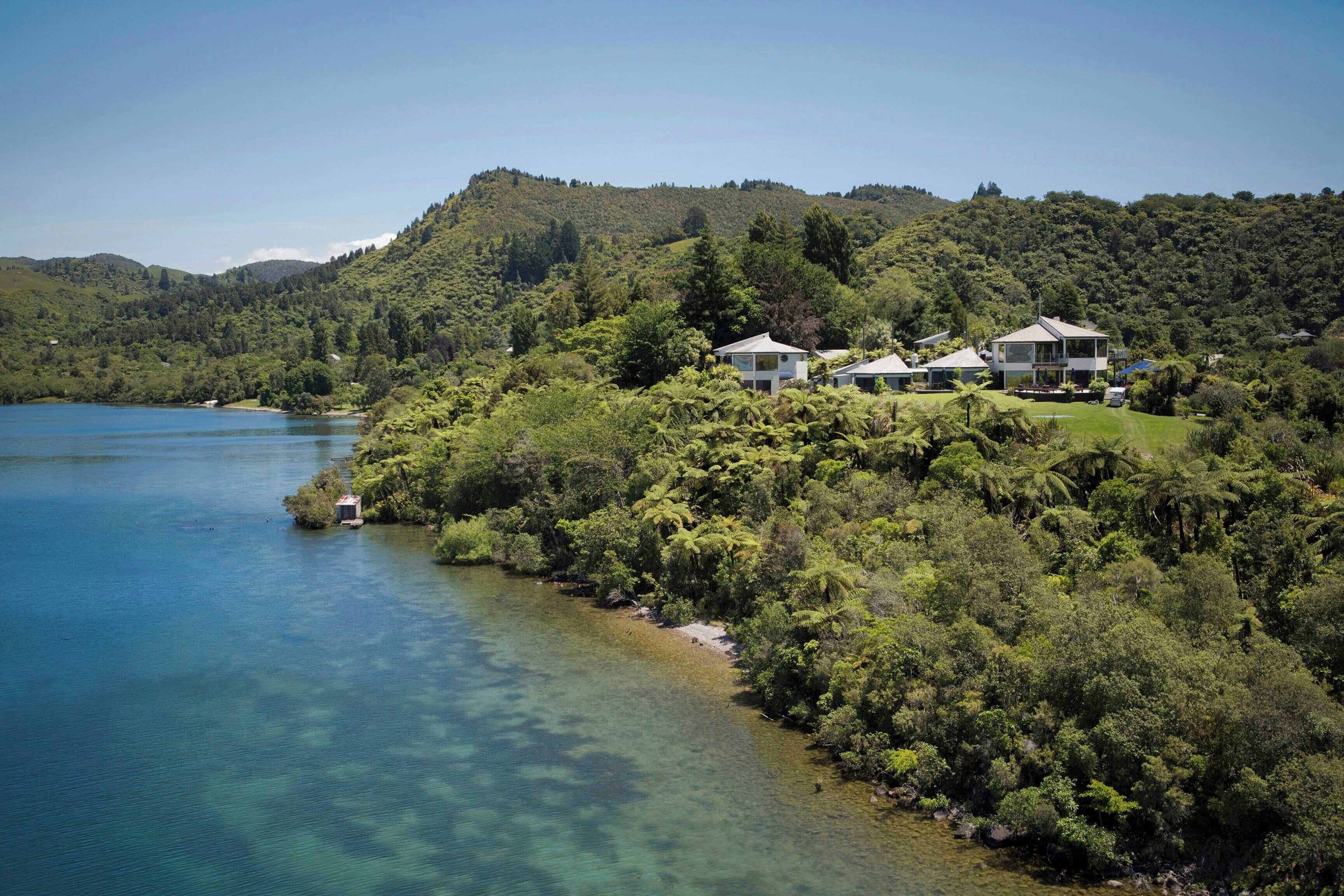 A coastal property with multiple houses surrounded by dense forest and a clear lake.