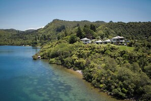 A coastal property with multiple houses surrounded by dense forest and a clear lake.