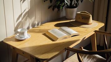 Una mesa de madera con un libro, un sombrero y una taza.