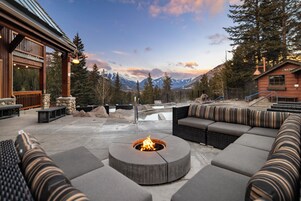 Un patio al aire libre con un brasero, asientos y vistas a las montañas.