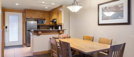 A compact kitchen with wooden cabinets, a built-in microwave, and a dining area with a wooden table and chairs.