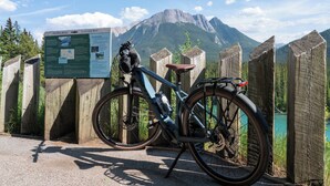 A bicycle parked next to a wooden fence with a signboard in the background.