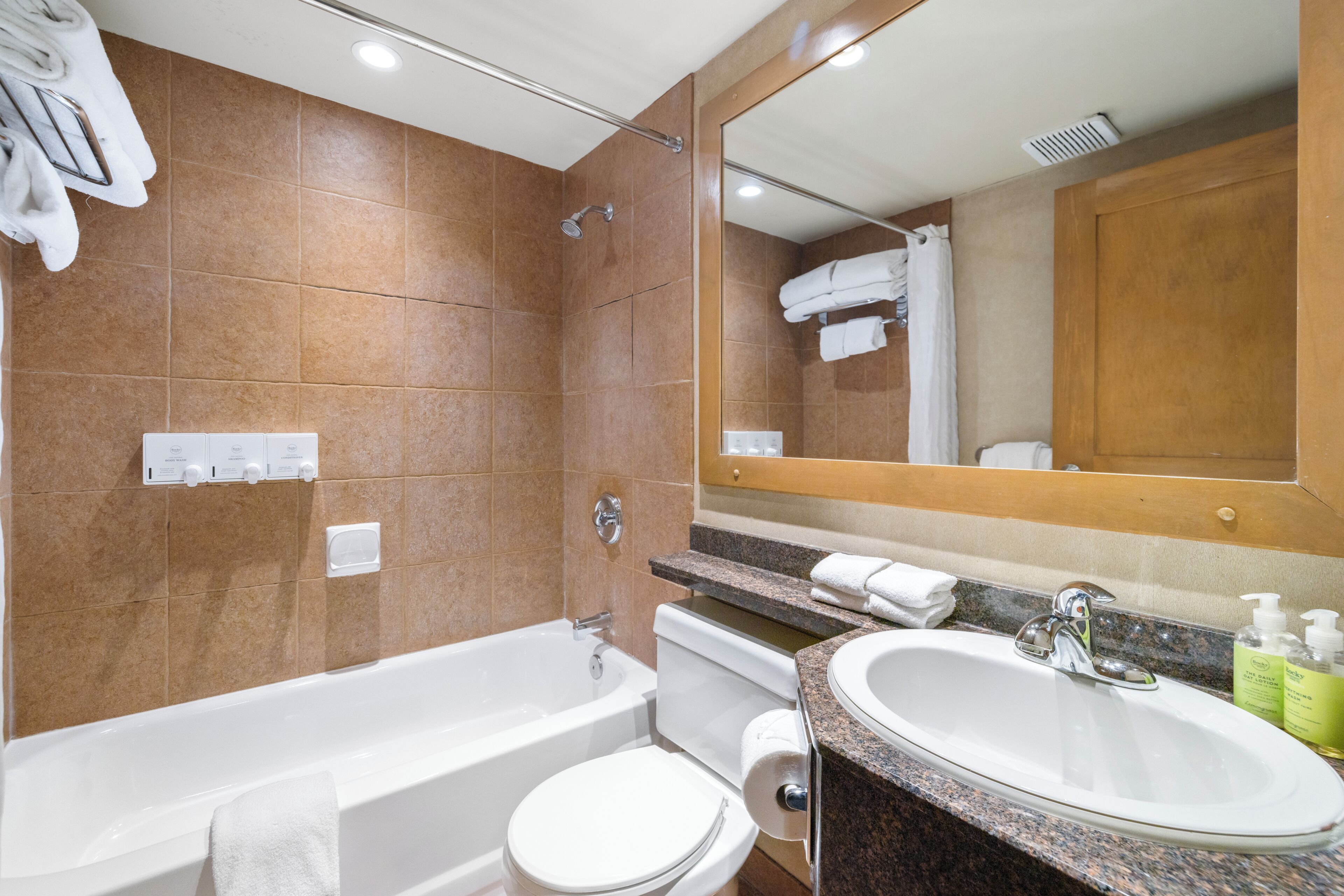 A bathroom with a bathtub, toilet, sink, and a large mirror.