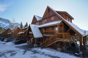 A lodge with a steeply pitched roof, wooden exterior, and a staircase leading to the entrance.