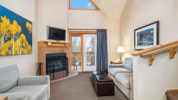 Un salon moderne avec une cheminée, un téléviseur et une grande fenêtre.