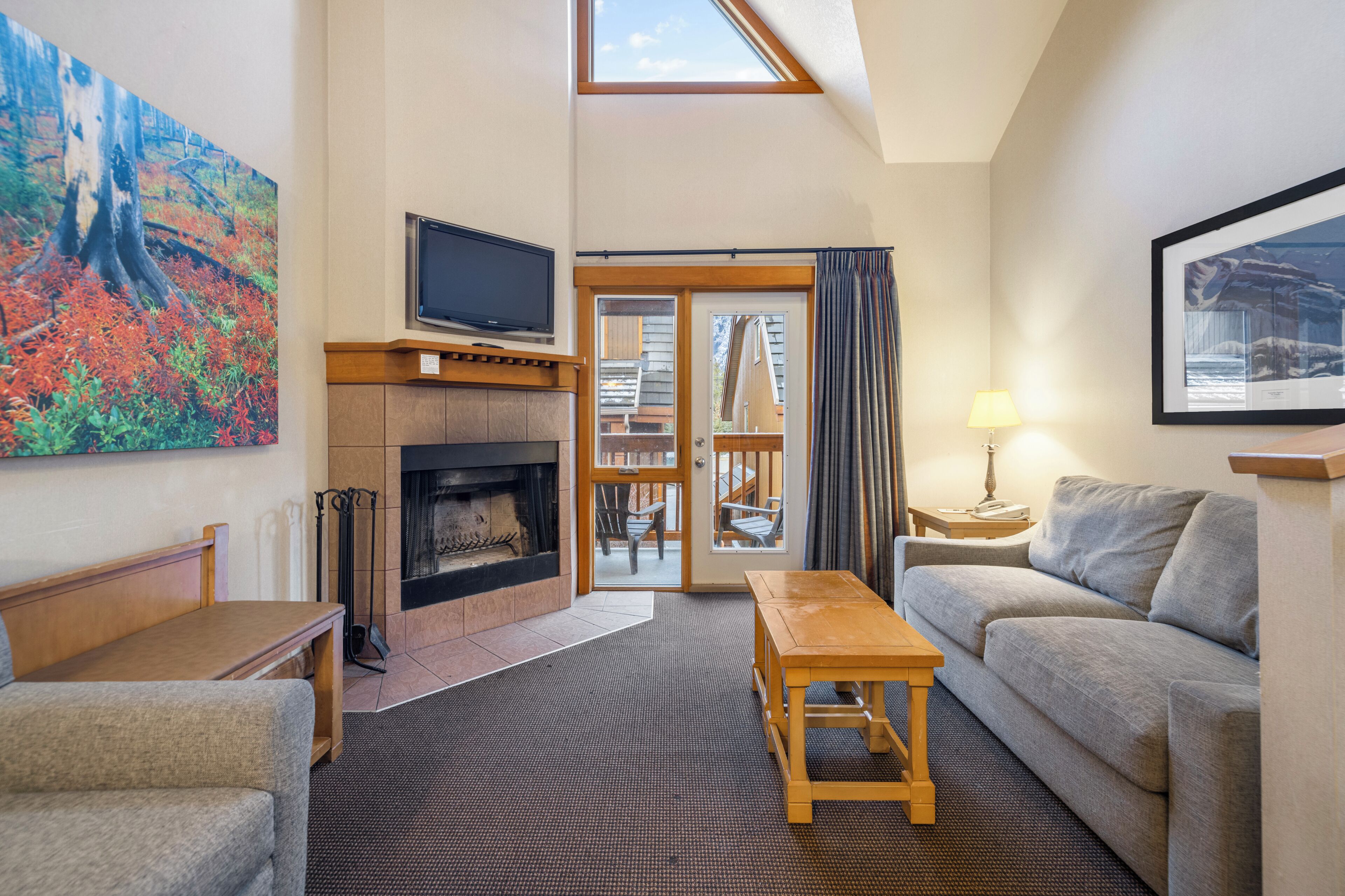 A living room with a fireplace, a television, a sofa, a coffee table, and a painting on the wall.