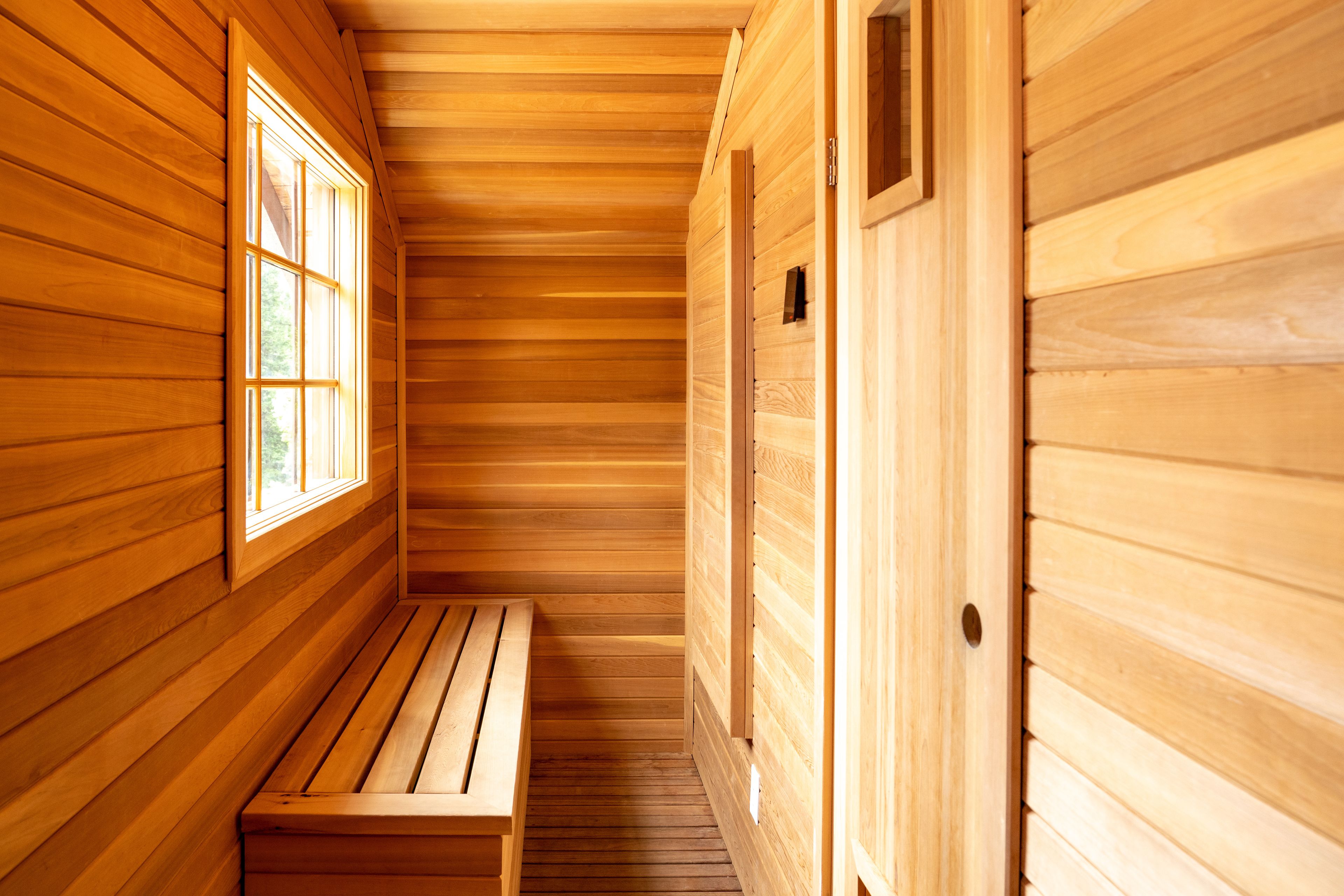 A wooden sauna room with a bench and a window.