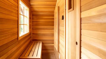 A wooden sauna room with a bench and a window.
