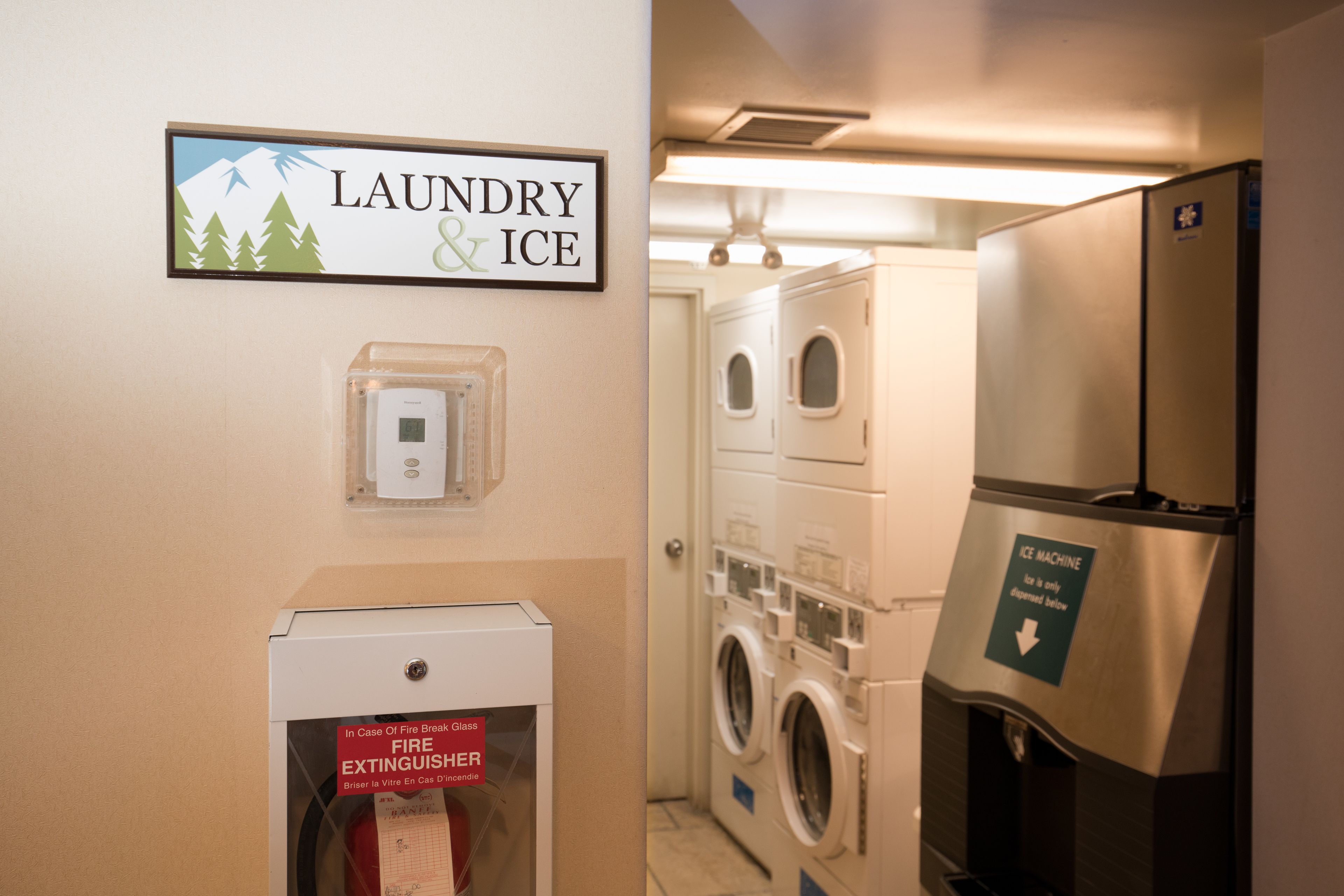 A laundry and ice machine area with a fire extinguisher and a sign indicating the location.