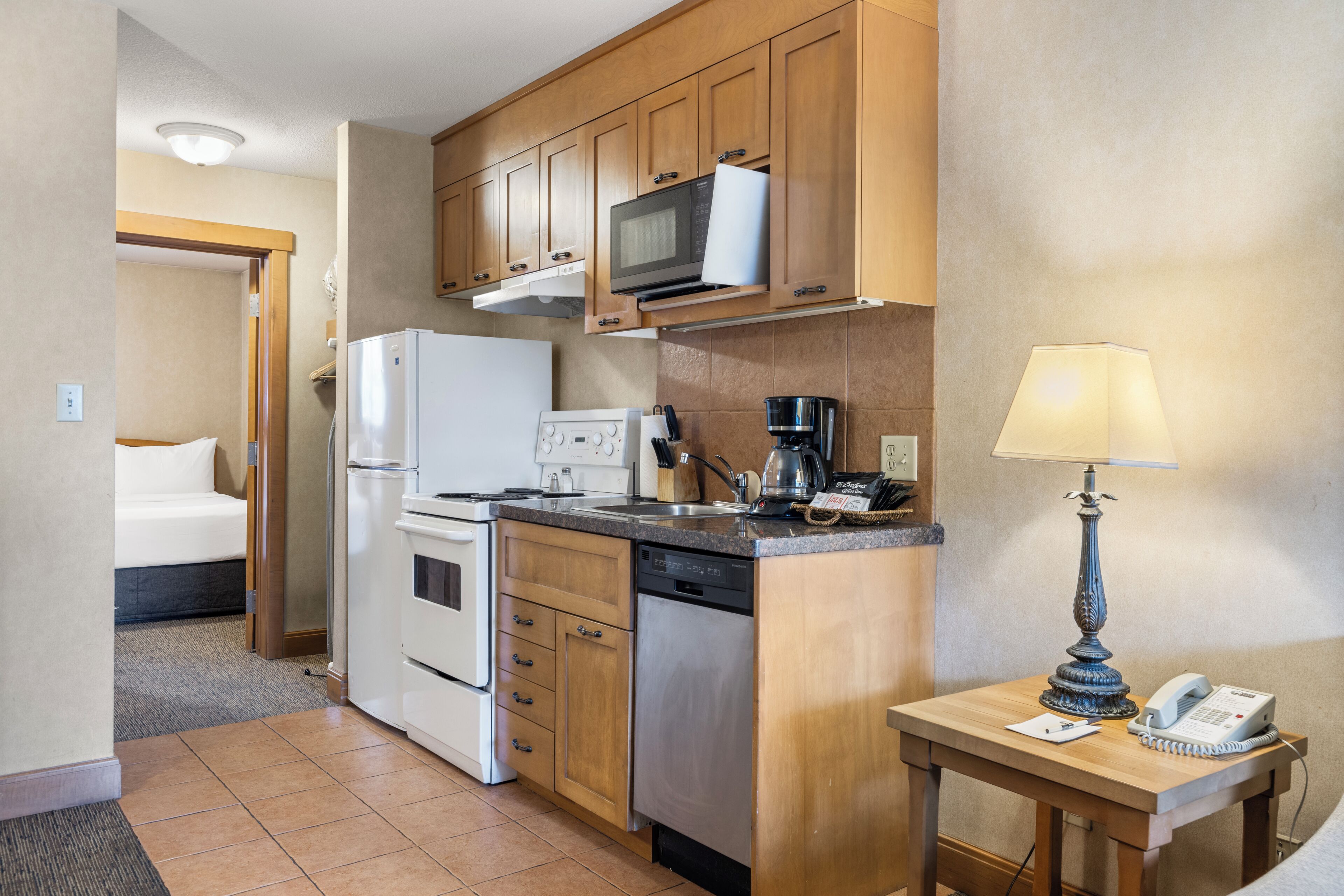 Una cocina compacta equipada con microondas, estufa, refrigerador y cafetera.