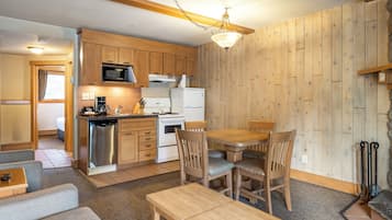 Una cocina compacta con armarios de madera, un microondas, una estufa y un refrigerador.