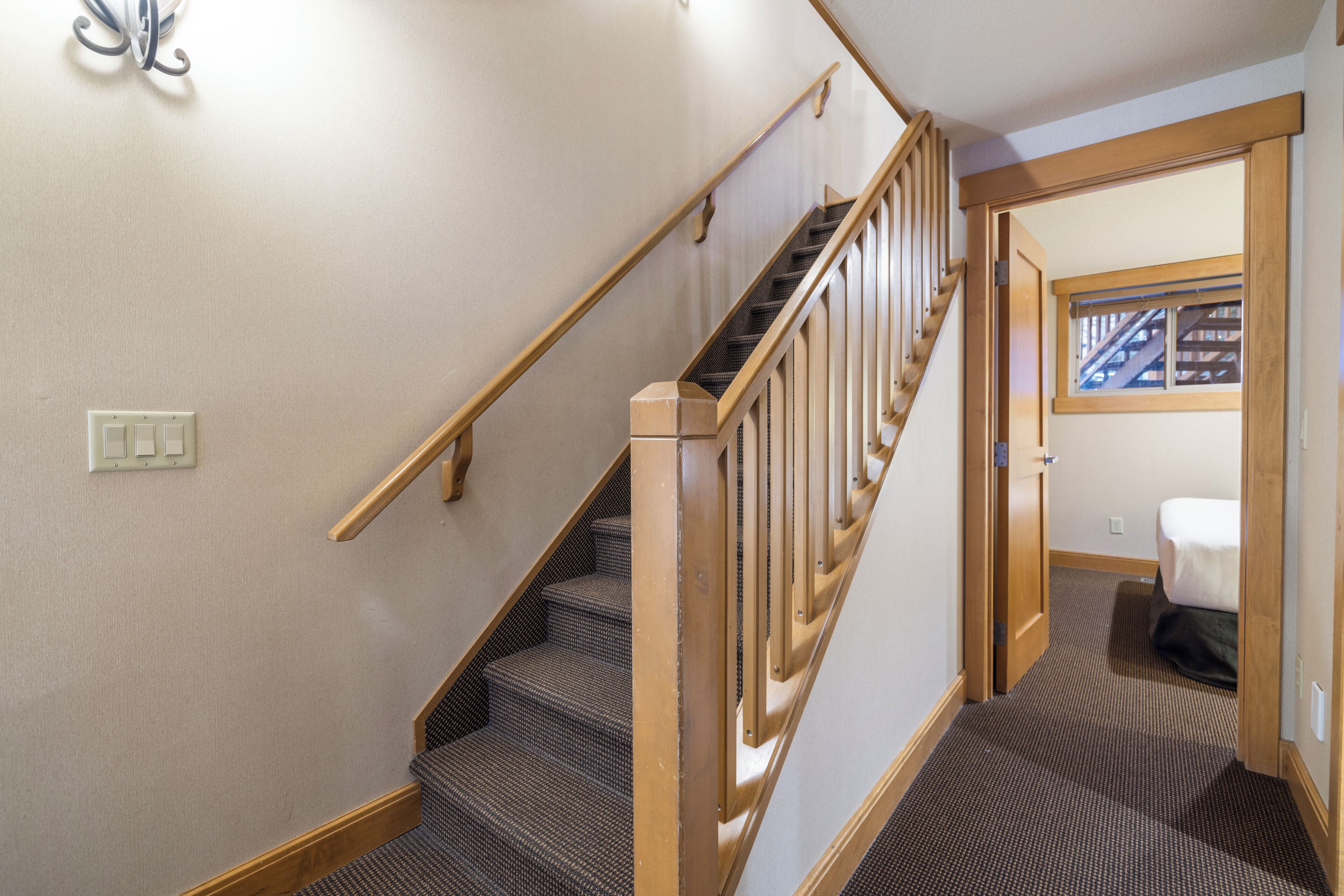 A carpeted staircase with wooden handrails and a carpeted landing area.