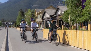Three cyclists riding on a street with wooden fences and buildings on the side.