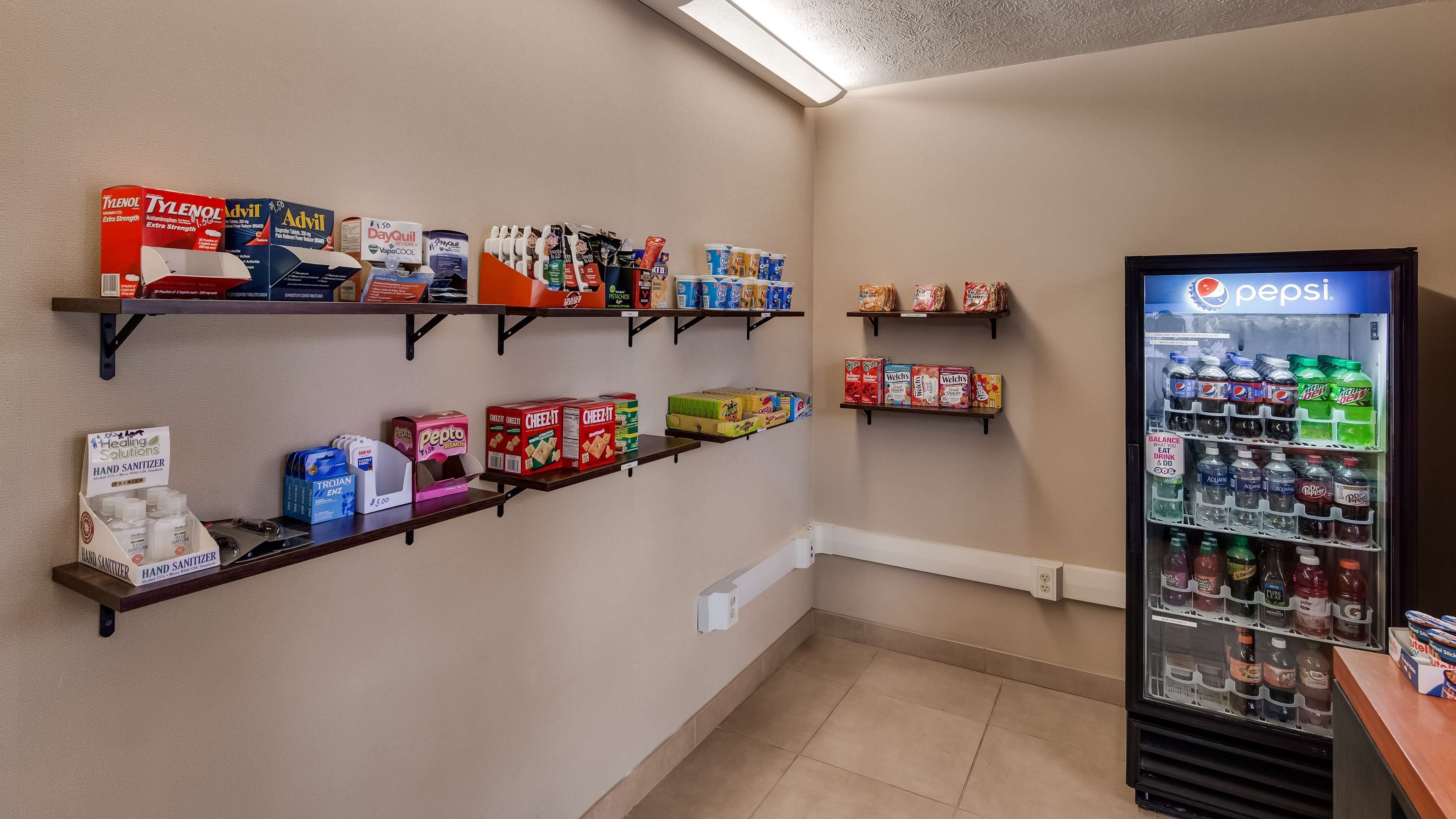 A snack and beverage station with shelves stocked with snacks, drinks, and hand sanitizers.