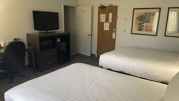 A hotel room with two beds, a desk with a television, a minibar, and a door with a lock.
