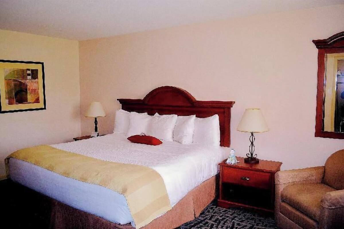 A hotel room with a bed, two bedside tables, a chair, and a painting on the wall.