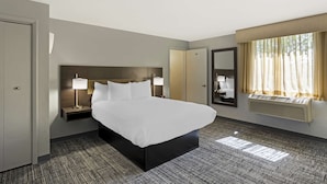 A hotel room with a large bed, bedside tables with lamps, a wardrobe, a mirror, and a window with curtains. - Best Western DuBois Hotel (DuBois)