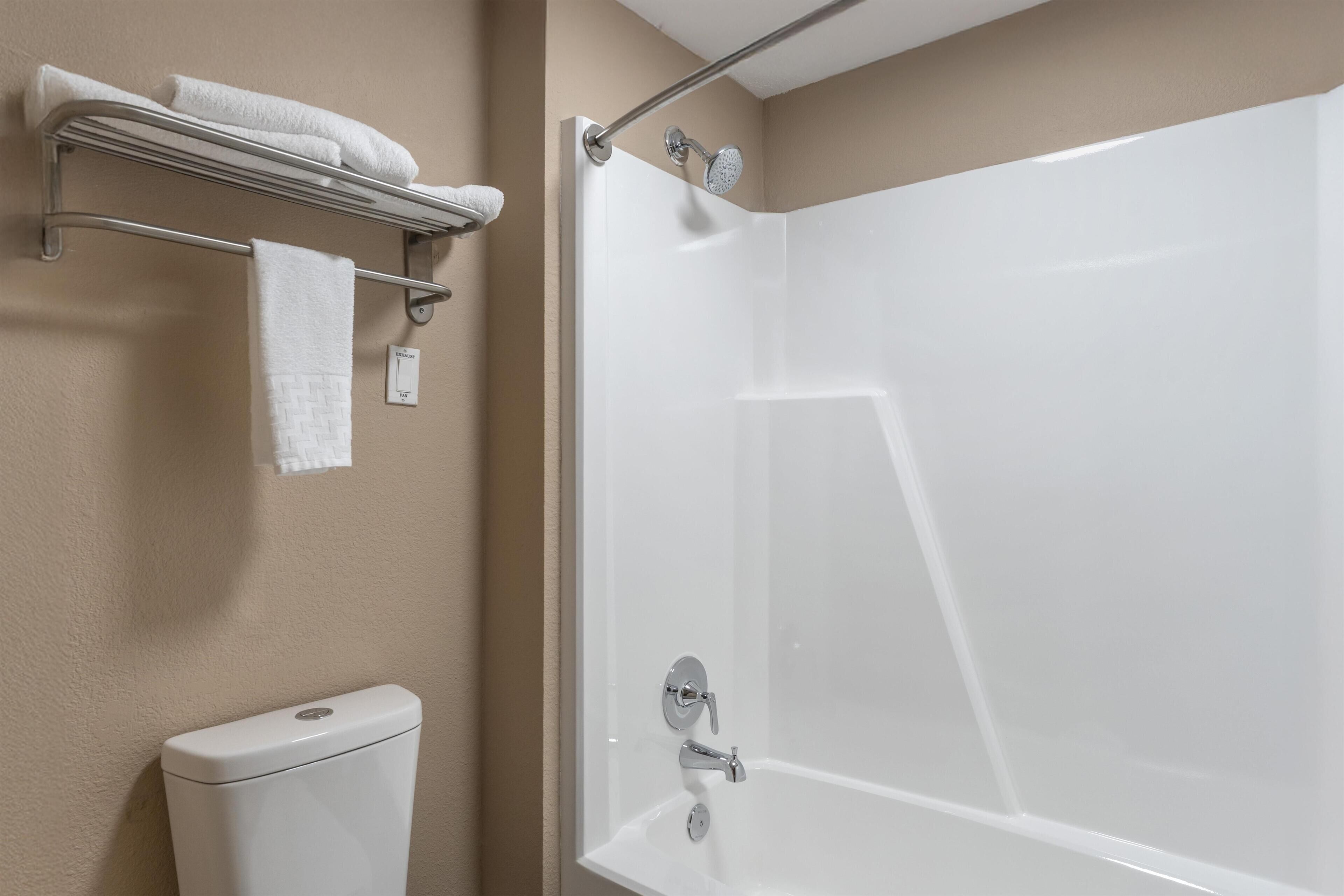A bathroom with a white bathtub, a toilet, and a towel rack with towels.