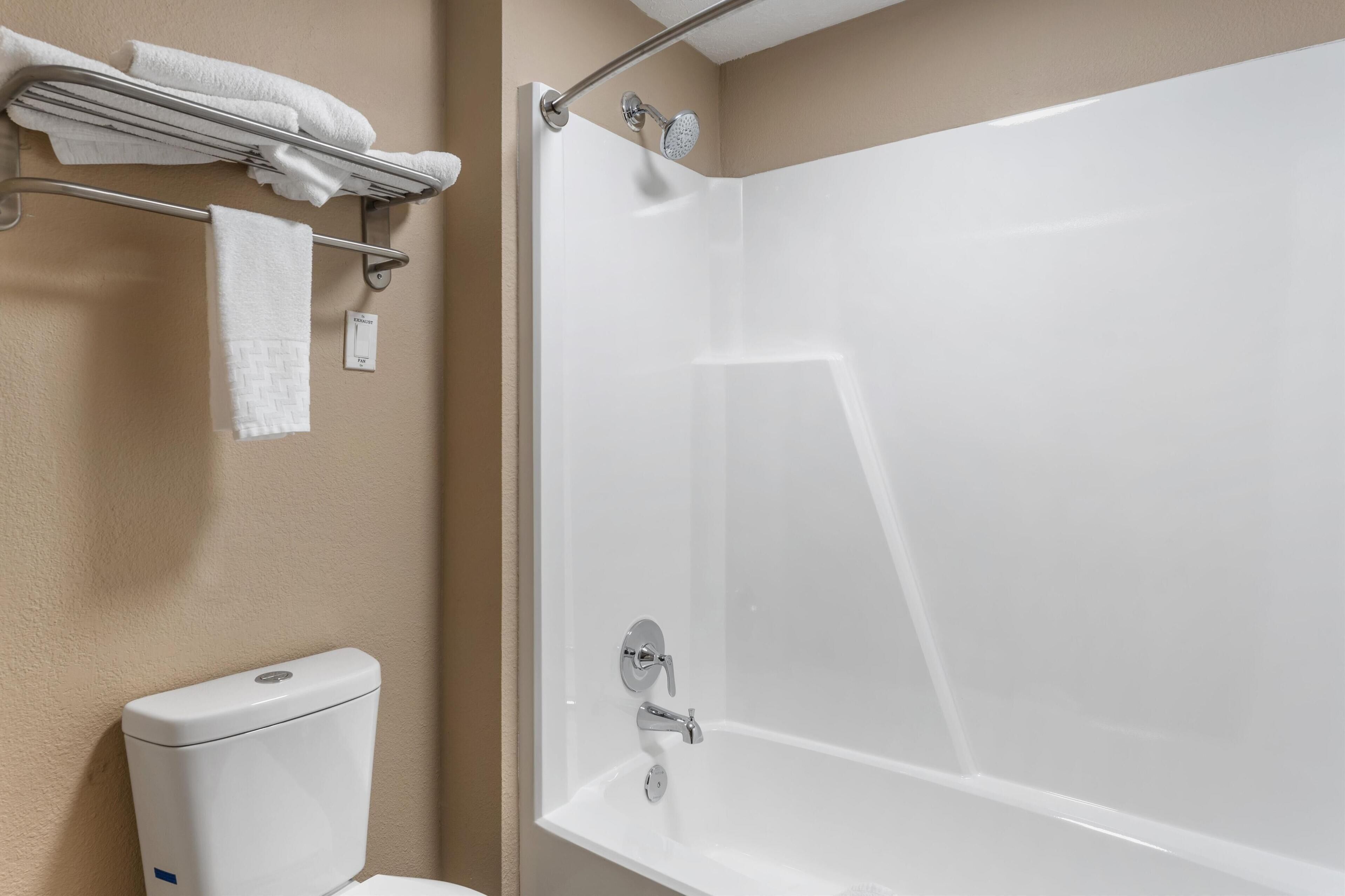Un baño con una bañera, un perchero con toallas y un inodoro.