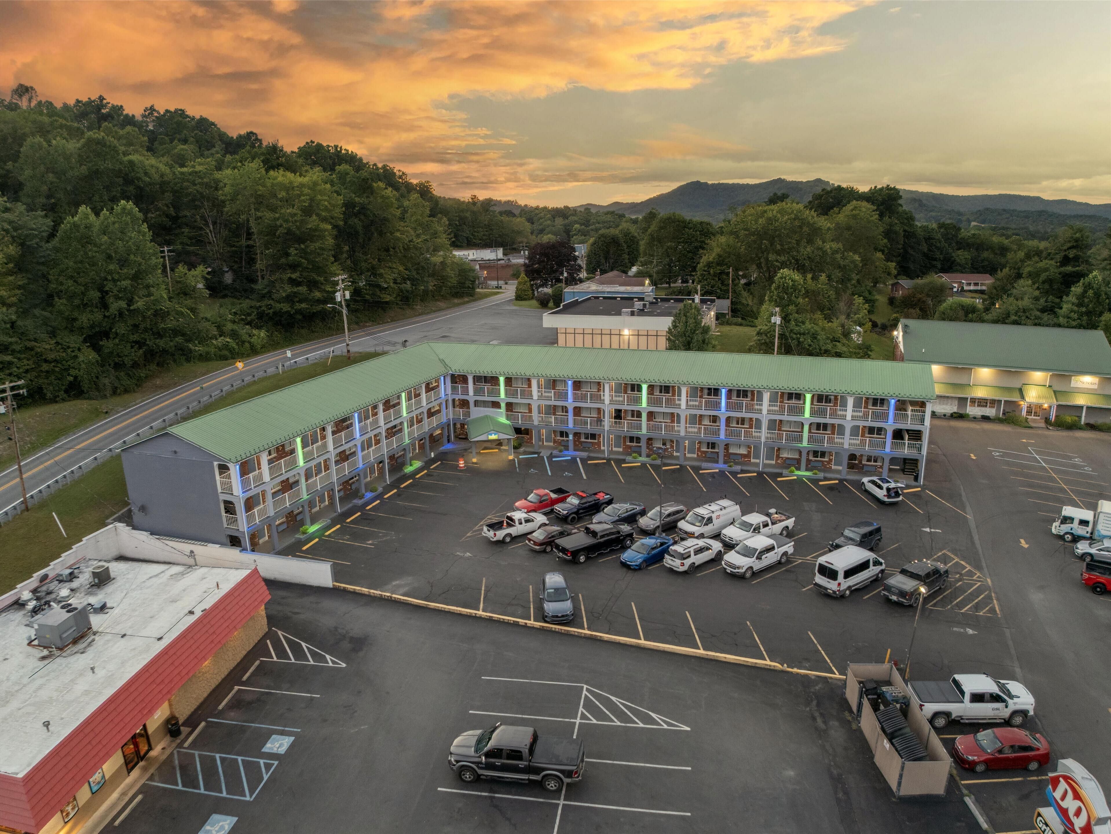 A multi-story motel with a green roof parking lot.