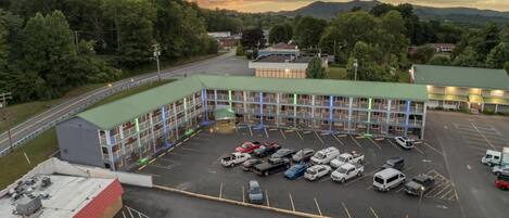 A multi-story motel with a green roof parking lot.