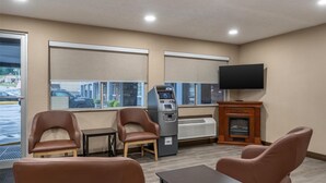 A hotel lobby with seating, an ATM, a fireplace, and a TV.
