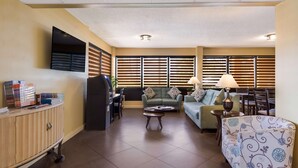 A living room with a sofa, a coffee table, a TV mounted on the wall, and a cabinet with items on top. - SureStay Hotel by Best Western St. Pete Clearwater Airport (Clearwater)