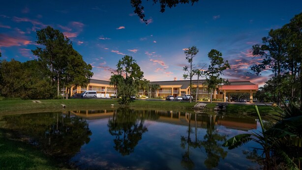A hotel with a reflection pool, surrounded by trees and a clear sky. - SureStay Hotel by Best Western St. Pete Clearwater Airport (Clearwater)