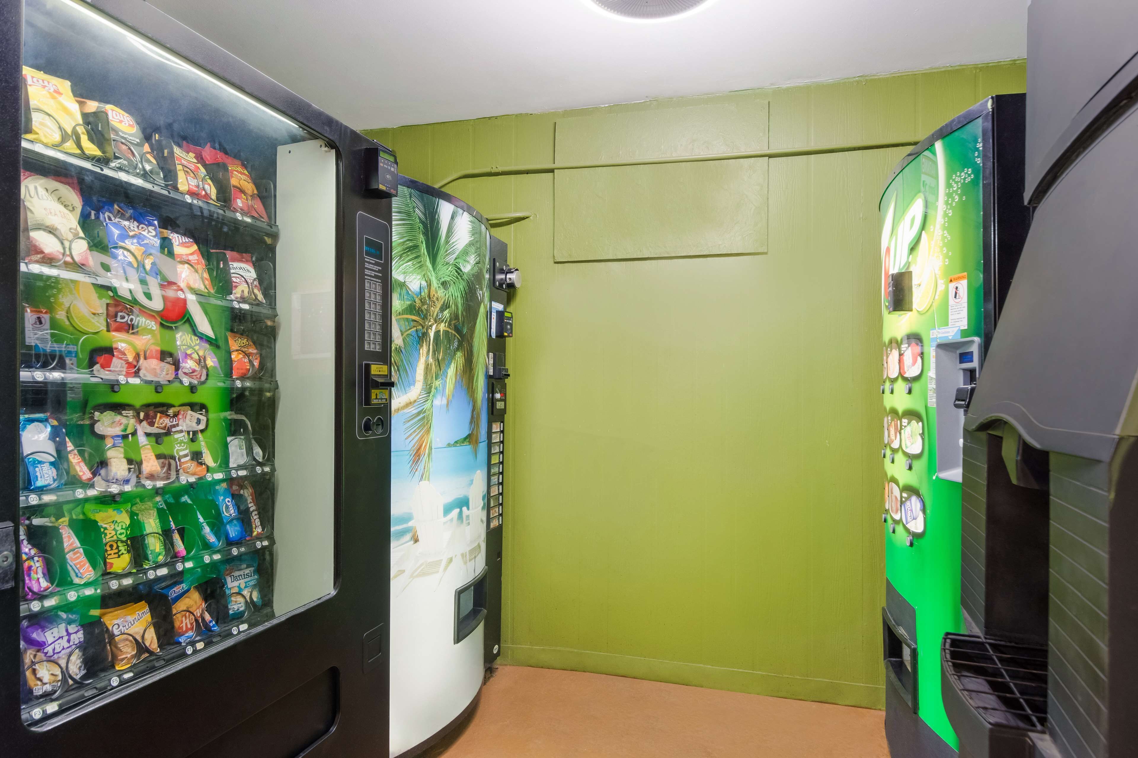 A vending machine area with snacks and drinks, green walls, and a palm tree mural.