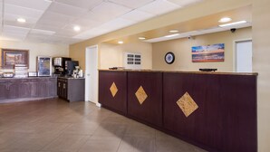 A reception area with a wooden counter, a clock, and a painting on the wall. - SureStay Hotel by Best Western St. Pete Clearwater Airport (Clearwater)