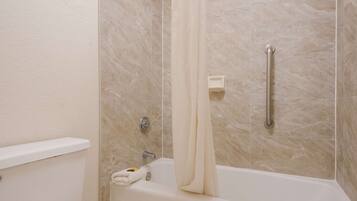 A bathroom with a bathtub, a shower curtain, a handrail, and a soap dish.