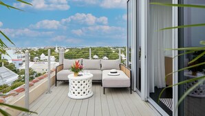 A balcony with a sofa, a round table, and a view of the cityscape. - La Concha Key West, Autograph Collection (Key West)