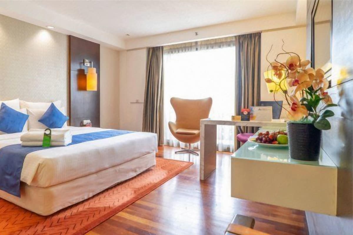 Een hotelkamer met een bed, een bureau, een stoel en een raam met gordijnen.