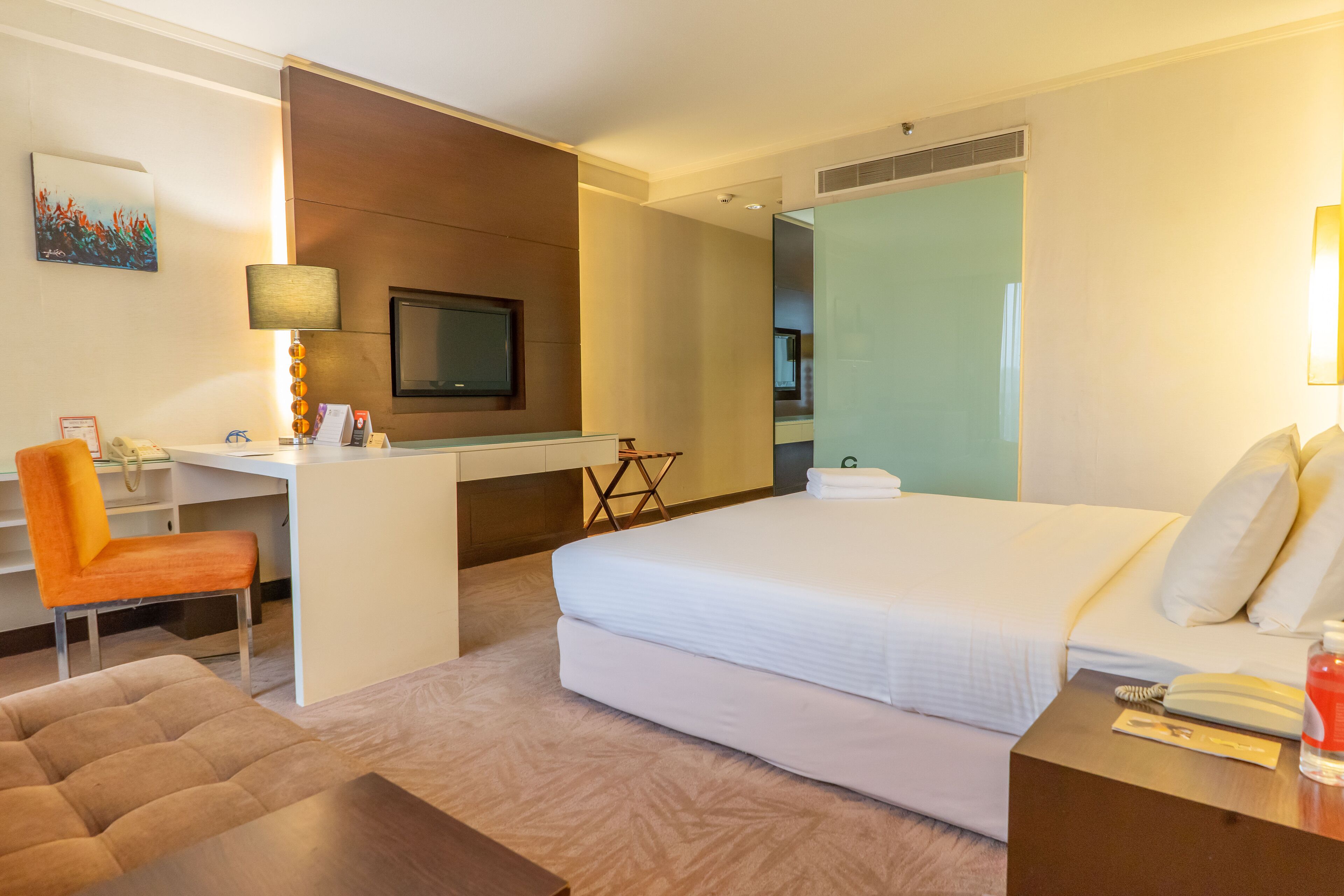 Ein Hotelzimmer mit Bett, Schreibtisch, Stuhl und Fernseher.