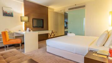 Ein Hotelzimmer mit Bett, Schreibtisch, Stuhl und Fernseher.