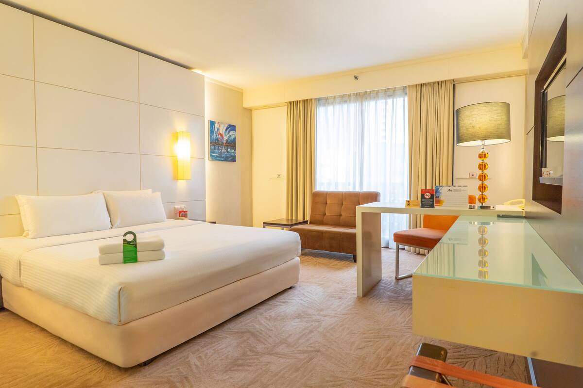 Hotelkamer met een groot bed, een bureau, een stoel, een lamp en een schilderij aan de muur.