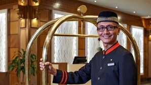 Een persoon in uniform houdt een gouden object vast, waarschijnlijk onderdeel van de hotelinrichting.