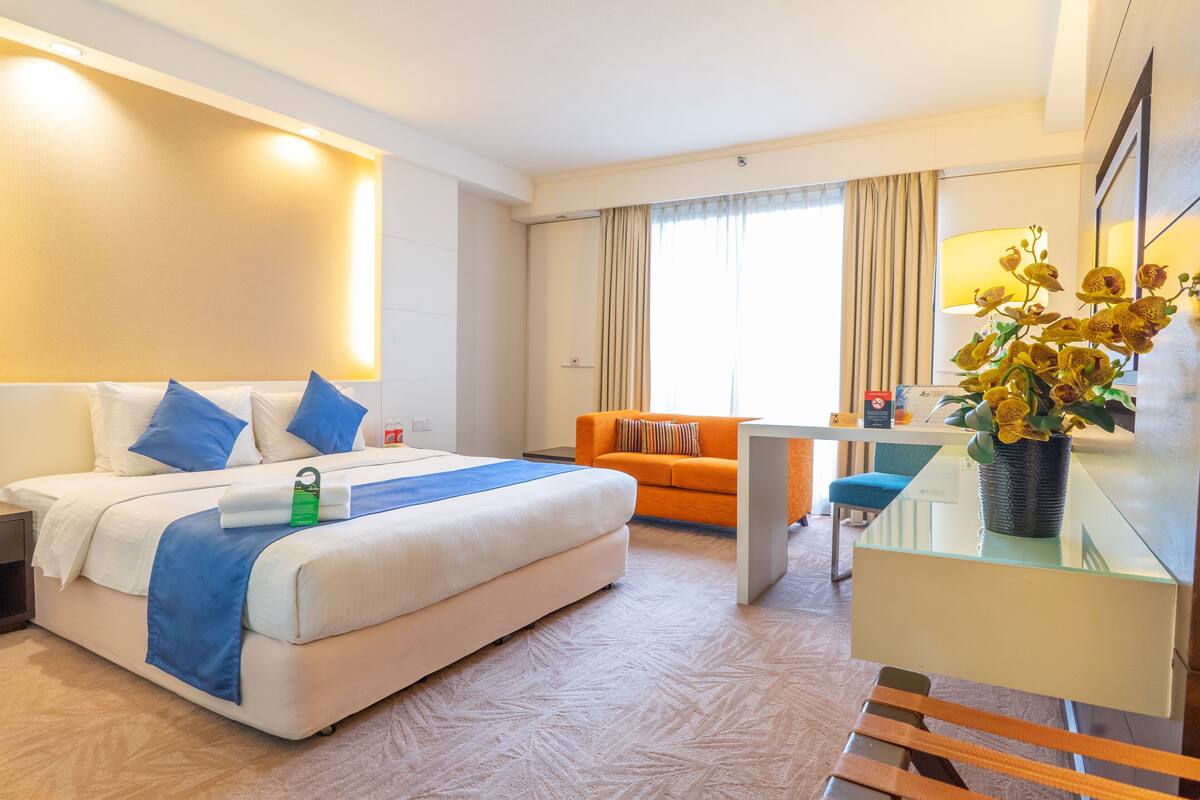 Een hotelkamer met een bed, een bureau, een stoel en een bank.