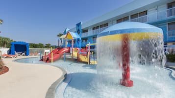 A water park with a large water fountain, a slide, and a pool area.