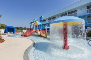 A water park with a large water fountain, a slide, and a pool area.