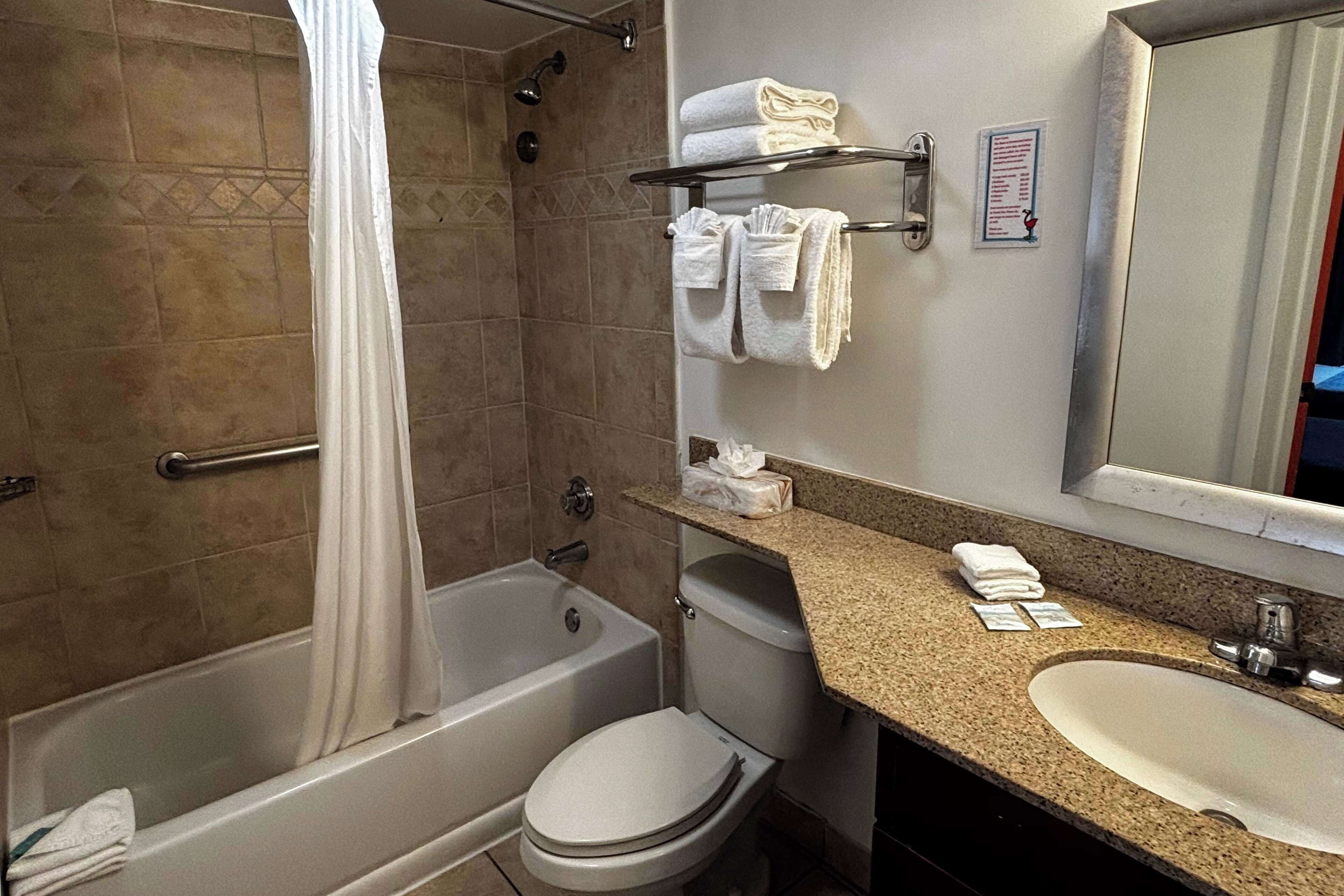 A bathroom with a bathtub, toilet, sink, and a towel rack with folded towels.