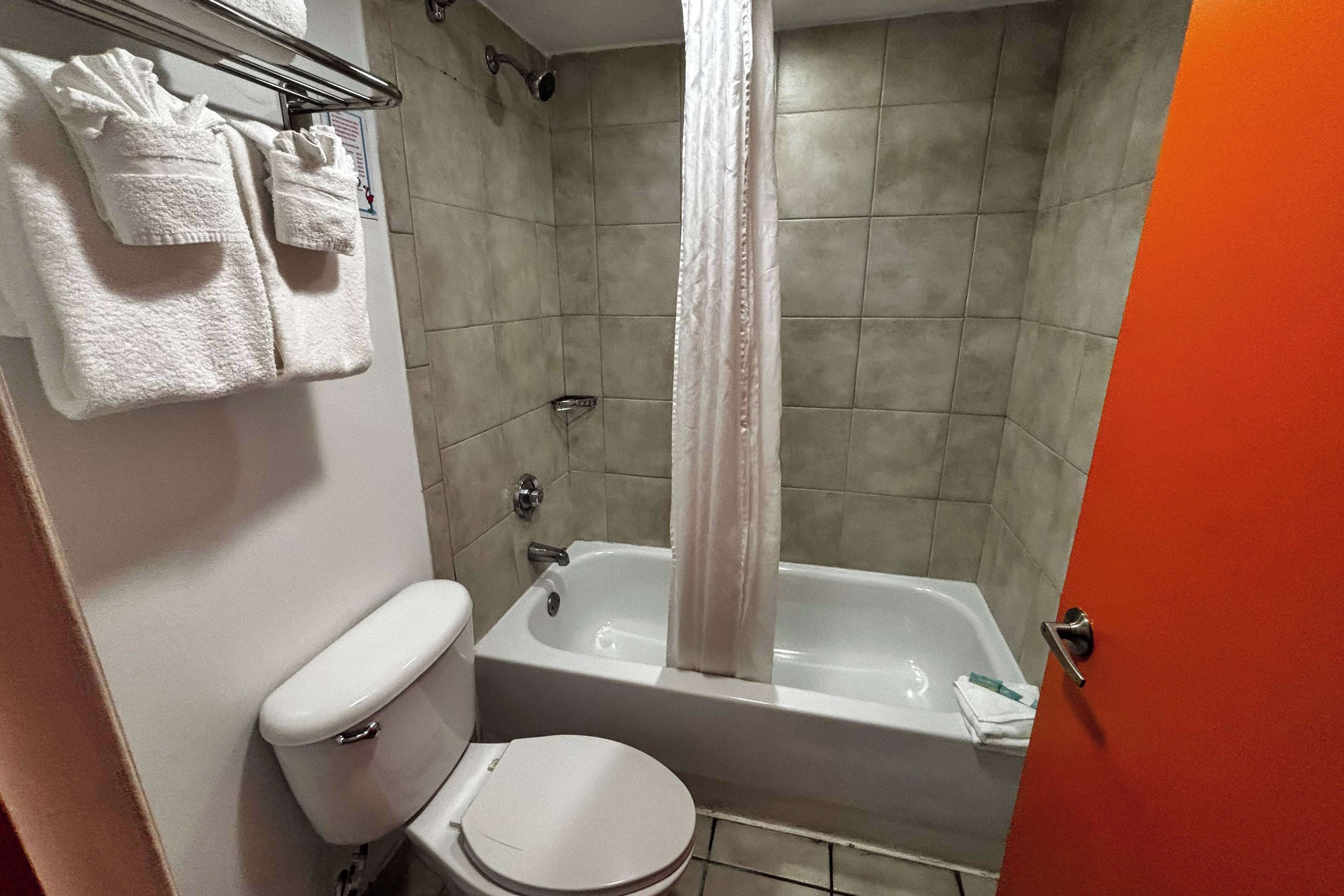 A bathroom with a toilet, bathtub, and a shower curtain.